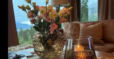 a vase with flowers in it sitting on a table at Modern cabin with panoramic view, sauna and fire pit in Espedalen