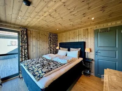 a bedroom with a bed in a room with wooden walls at Modern cabin with panoramic view, sauna and fire pit in Espedalen