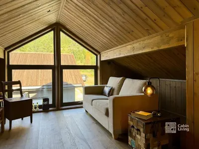 a living room with a couch and a large window at Modern cabin with panoramic view, sauna and fire pit in Espedalen