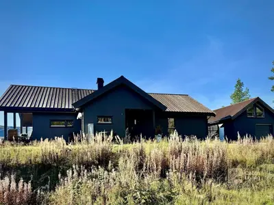 a blue house in a field of tall grass at Modern cabin with panoramic view, sauna and fire pit in Espedalen