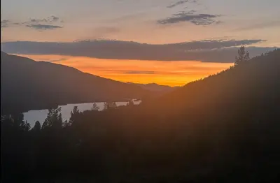 a sunset over a mountain range with a lake at Modern cabin with panoramic view, sauna and fire pit in Espedalen