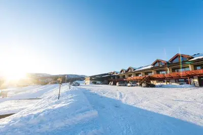 a snow covered street with a lodge in the background at Skarslia Apartment in Skarsgård