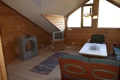 a living room with a couch and a tv in a attic at Skarslia Apartment in Skarsgård