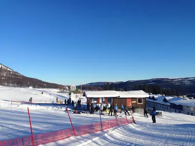 a group of people in the snow near a ski lodge at Skarslia Apartment in Skarsgård