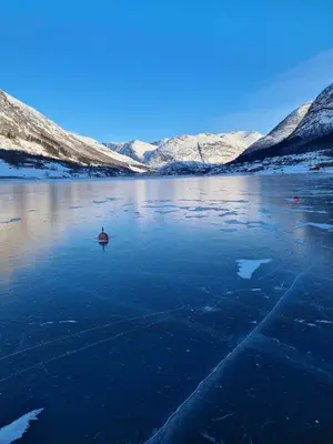 a person in a boat on a lake with snow covered mountains at JOlster apartaments - lake view in Årdal