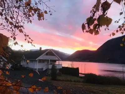 a house on the shore of a lake at sunset at JOlster apartaments - lake view in Årdal