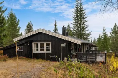 a black house in the middle of a forest at Fageråsen 209 by Vacation Trysil in Trysil