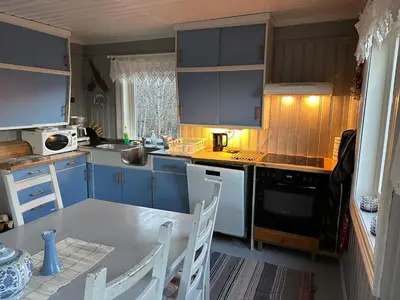 a kitchen with blue cabinets and a table and chairs at Cosy farmhouse with spa as add on service in Gjøvik