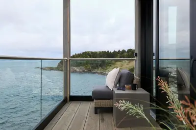 a living room with a view of the water at Hideaway Herdla luxurious cabins 15 m above the sea in Herlø