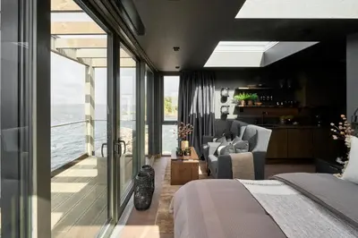 a bedroom with a bed and a view of the ocean at Hideaway Herdla luxurious cabins 15 m above the sea in Herlø
