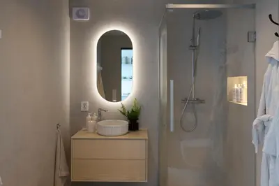 a bathroom with a sink and a shower with a mirror at Hideaway Herdla luxurious cabins 15 m above the sea in Herlø