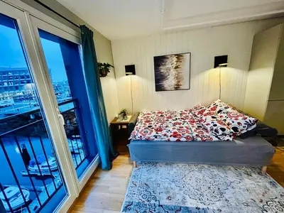 a bedroom with a bed and a large window at Riverside family-friendly Mini Penthouse in Trondheim
