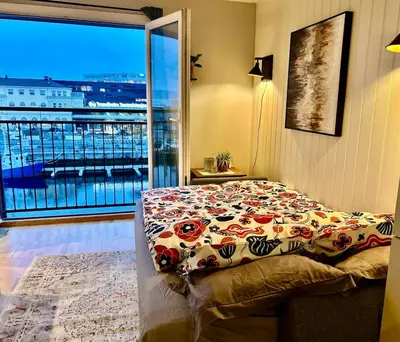 a bedroom with a bed and a large window at Riverside family-friendly Mini Penthouse in Trondheim
