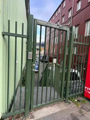 a green gate in front of a building at Riverside family-friendly Mini Penthouse in Trondheim