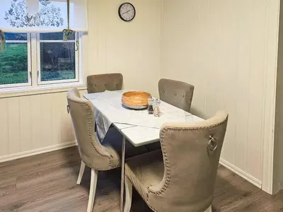 a dining room table with chairs and a clock on the wall at Charming Farm Stay On Averøy Island in Averoy