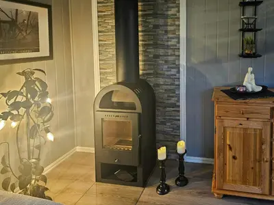 a wood burning stove in a room with a wall at Charming Farm Stay On Averøy Island in Averoy