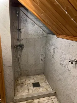 a bathroom with a shower with a stone floor at Fengselet Gjestegård in Leira