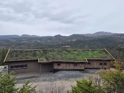 a building with a green roof with mountains in the background at Modern mountain cabin with panorama view in Eggedal