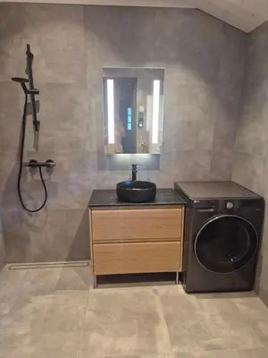 a bathroom with a washing machine and a sink at Modern mountain cabin with panorama view in Eggedal