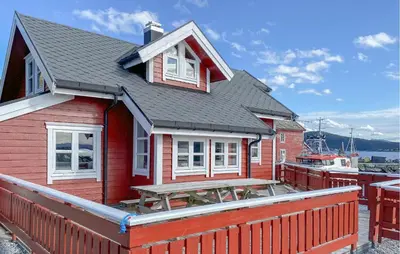 a red house with a picnic table on a deck at 4 Bedroom Lovely Home In Leinøya in Fosnavåg