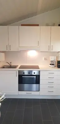 a kitchen with white cabinets and a black oven at Et golfslag fra Stiklestad Golfklubb in Verdal