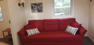 a red couch in a living room with two pillows at Et golfslag fra Stiklestad Golfklubb in Verdal