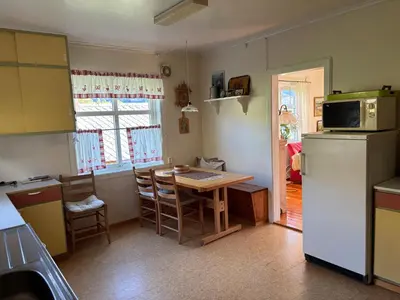 a kitchen with a table and a refrigerator at Jåstad Gjestetun in Jåstad