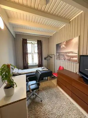 a room with a bed and a desk and a tv at Modern and spacious home in Trondheim