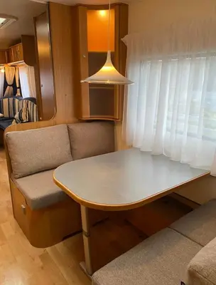 a small kitchen with a table and a couch at Aurora Caravan Near Bergen in Strusshamn