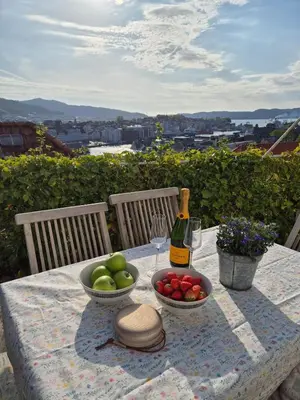 a table with two bowls of apples and a bottle of wine at 2-roms leilighet med spektakulær utsikt og privat hage in Bergen