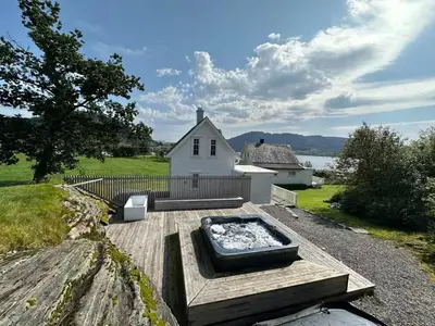 a hot tub on a wooden deck in front of a house at Architectural gem with fjord view in Holmedal