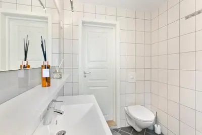 a white bathroom with a toilet and a sink at Centrum Apartment in Ålesund