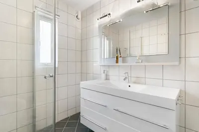 a white bathroom with a sink and a mirror at Centrum Apartment in Ålesund