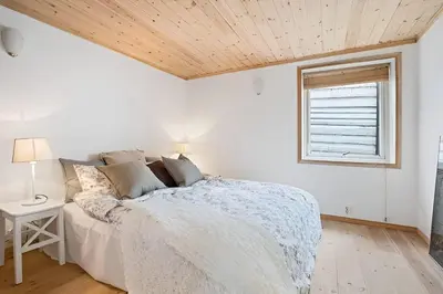 a white bedroom with a bed and a window at Historic Apartment in the Heart of Bergen in Bergen