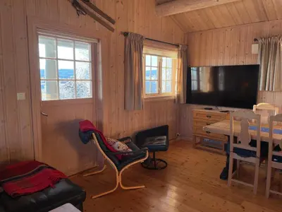 a living room with a television and a table and chairs at Koselig Og Sentral Hytte Med Peis Og Badstue in Beitostøl
