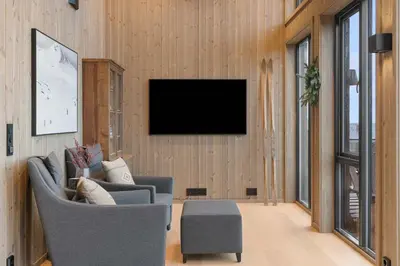 a living room with two chairs and a television on a wall at Mountain Chalet 958 by Vacation Trysil in Trysil