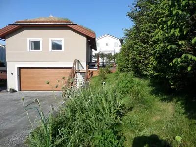 a house with a wooden garage door in front of a yard at Solstrand Fjord Holiday in Eidsvåg