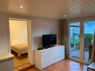 a room with a television on a dresser with a bed at Solstrand Fjord Holiday in Eidsvåg