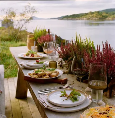 a table with plates of food and glasses of wine at Kyn Sjøstuer in Stavang
