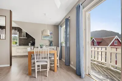 a kitchen and dining room with a table and a balcony at Eldur Seaside Cabin in Stavang