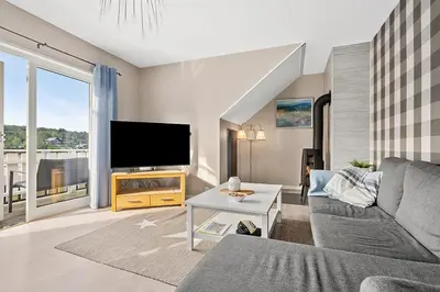 a living room with a couch and a flat screen tv at Eldur Seaside Cabin in Stavang