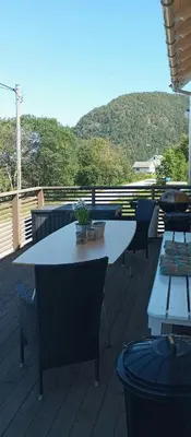 a table and chairs on a deck with a mountain at Renovated Chapel With Fjord Views In Vågstranda in Reistad