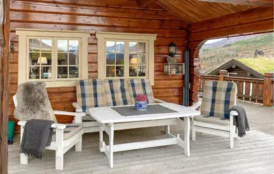 a porch with a table and chairs on a cabin at 3 Bedroom Beautiful Home In Straumgjerde in Brunstad