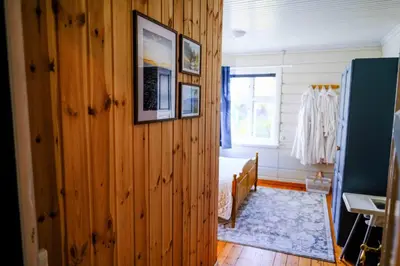 a room with a wooden wall with a bed and a window at Leave It All in Venabygd