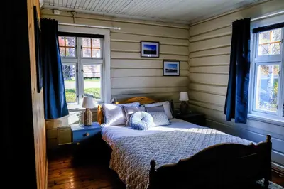 a bedroom with a bed with blue curtains and two windows at Leave It All in Venabygd
