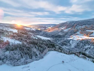 a view of a snow covered mountain with the sun setting at Leave It All in Venabygd