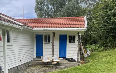 a small white house with blue doors and two chairs at Cozy Home In Førde I Hordaland in Erve