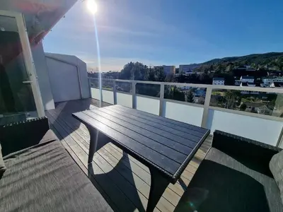 a deck with a wooden bench on a balcony at Beautiful 2-bedroom apartment in Bergen