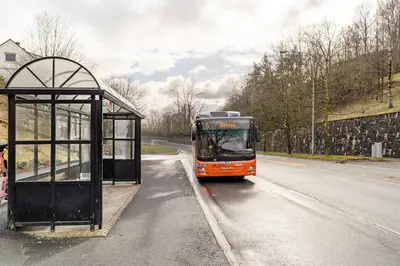 an orange bus is parked at a bus stop at Beautiful 2-bedroom apartment in Bergen