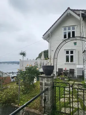a white house with a black fence and a yard at Cozy house in historical area in Bergen